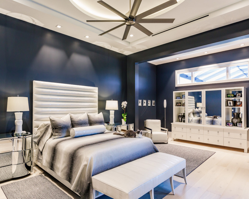 Example of a trendy master light wood floor, beige floor and tray ceiling bedroom design in Tampa with blue walls