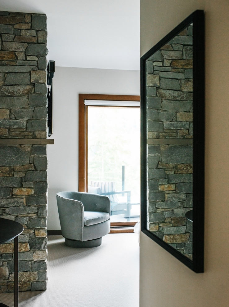 Inspiration pour une grande chambre design avec un mur gris, une cheminée standard, un manteau de cheminée en pierre et un sol gris.