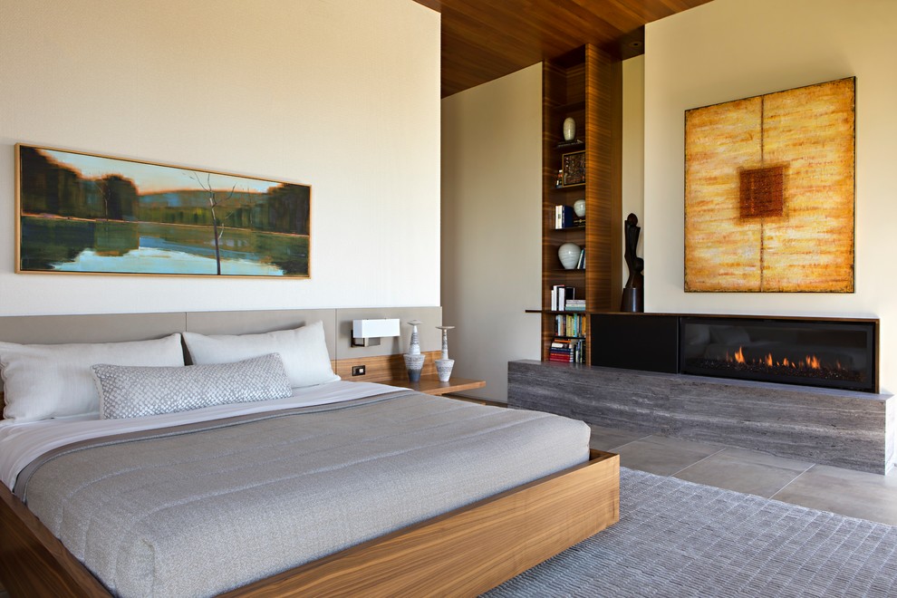 Example of a large trendy master gray floor and limestone floor bedroom design in Phoenix with beige walls, a ribbon fireplace and a stone fireplace