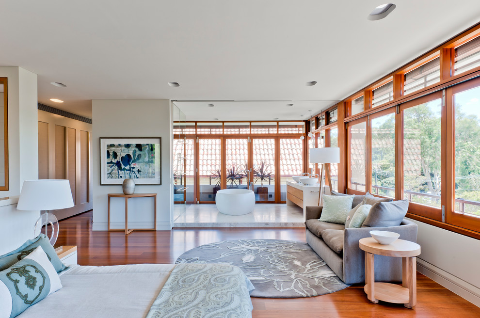 Großes Modernes Hauptschlafzimmer mit weißer Wandfarbe, braunem Holzboden und braunem Boden in Sydney