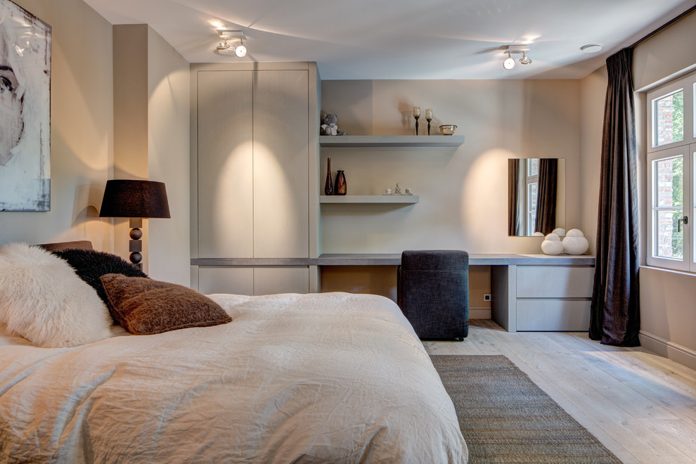 Modelo de dormitorio contemporáneo con paredes beige y suelo de madera clara
