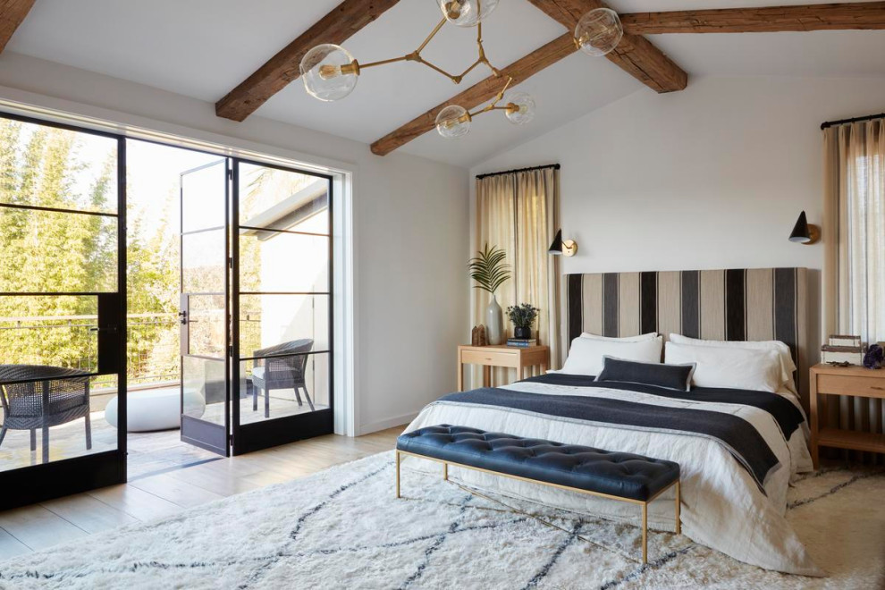 Modelo de dormitorio abovedado campestre con paredes blancas, suelo de madera en tonos medios, suelo marrón y vigas vistas