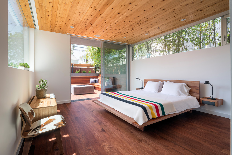 Diseño de dormitorio moderno con paredes blancas, suelo de madera oscura y suelo marrón