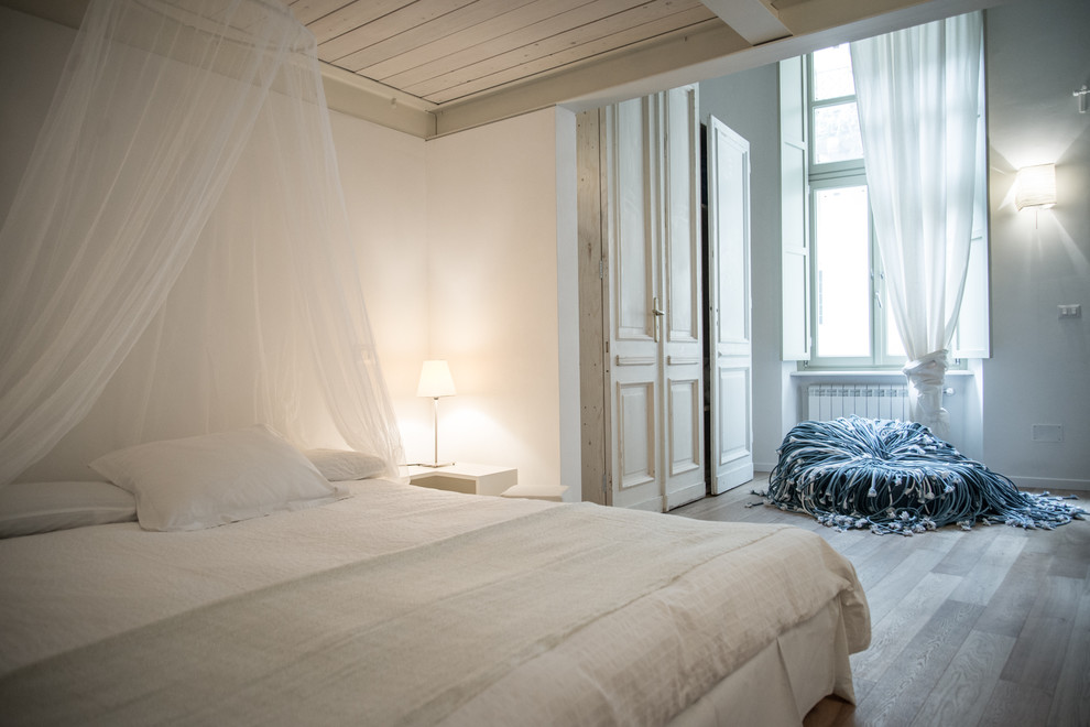 Ispirazione per una camera da letto stile loft contemporanea di medie dimensioni con pareti bianche, pavimento in legno massello medio e nessun camino