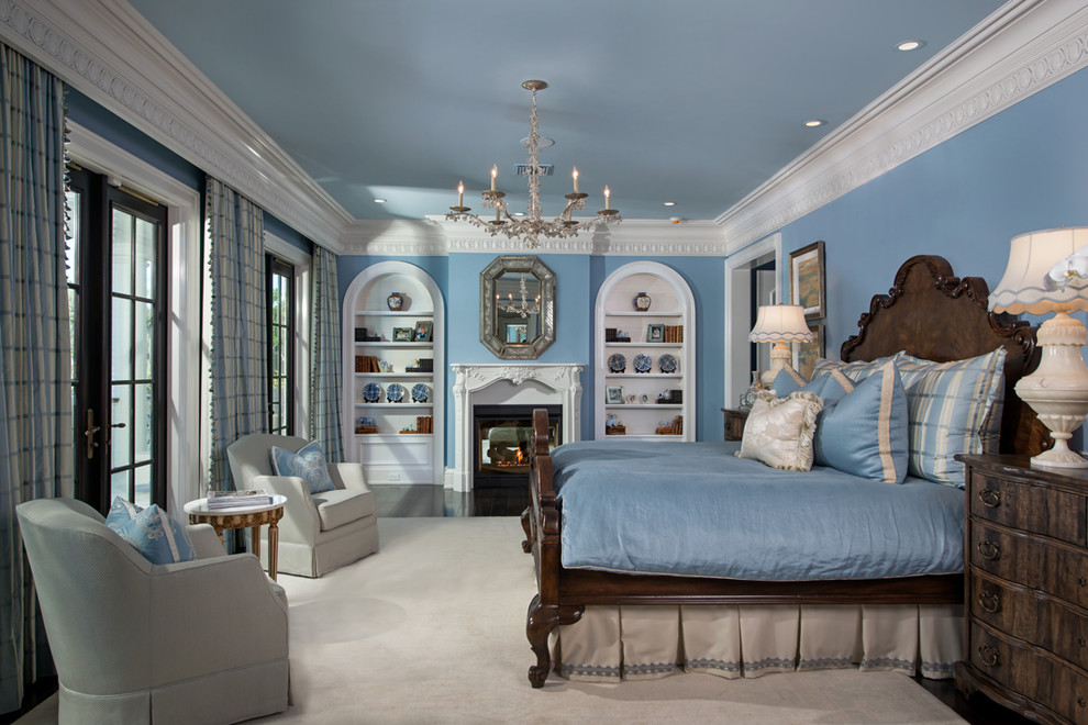 Идея дизайна: большая хозяйская спальня в классическом стиле с синими стенами, темным паркетным полом, стандартным камином и фасадом камина из штукатурки