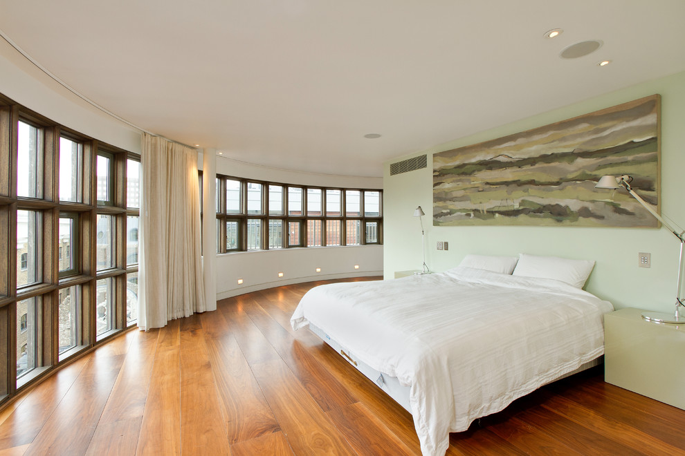 Idée de décoration pour une chambre design avec un mur vert et un sol en bois brun.