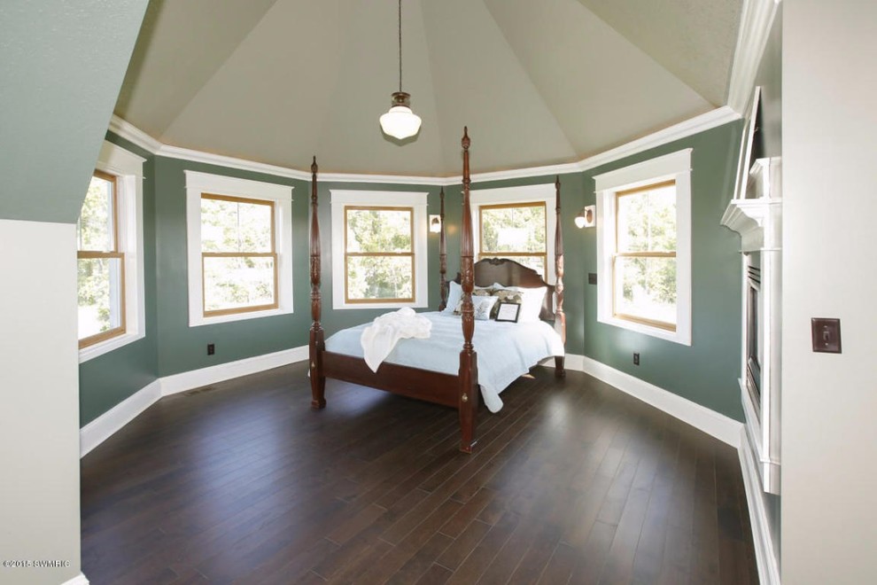 Cette image montre une grande chambre parentale victorienne avec un mur vert et parquet foncé.