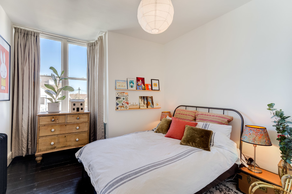 Imagen de dormitorio clásico renovado con paredes blancas, suelo de madera pintada y suelo negro