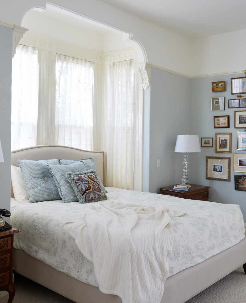 This is an example of a large victorian master bedroom in San Francisco with blue walls, carpet and beige floors.