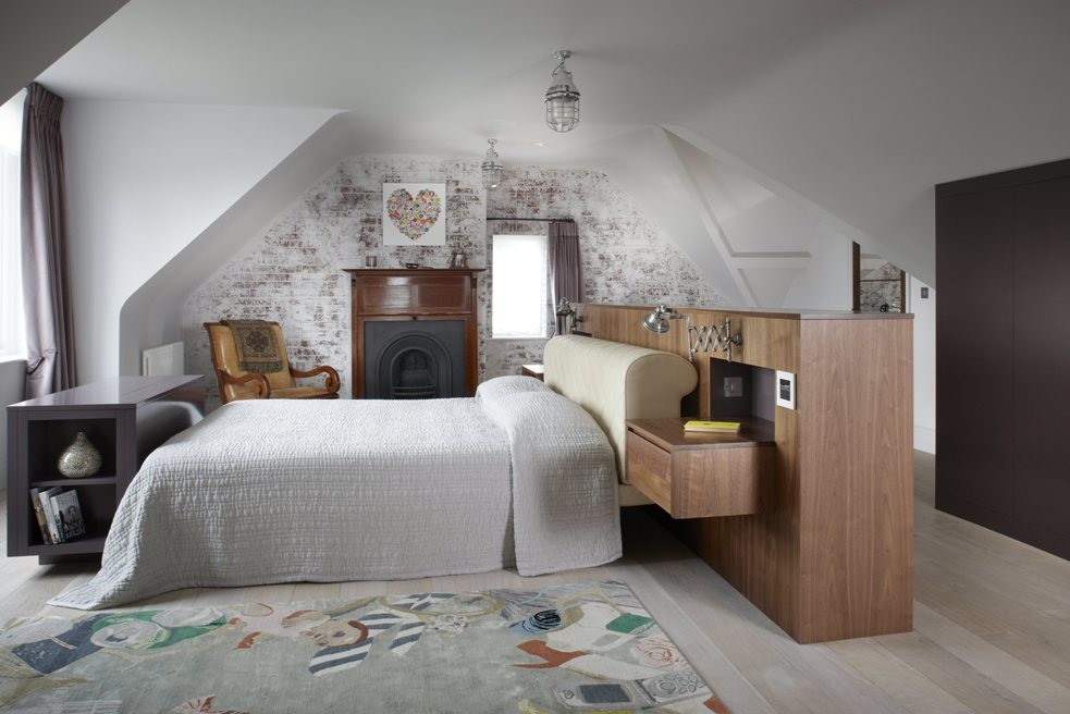 Modelo de dormitorio principal bohemio de tamaño medio con paredes blancas, suelo de madera pintada, todas las chimeneas y marco de chimenea de madera