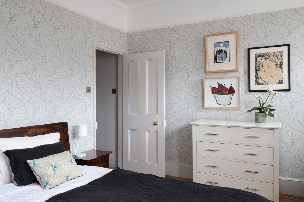 Großes Modernes Hauptschlafzimmer mit blauer Wandfarbe, braunem Holzboden, Kamin, gefliester Kaminumrandung und braunem Boden in London