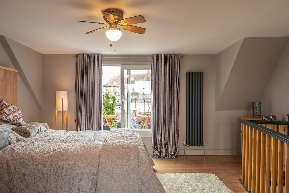 ケントにある広いコンテンポラリースタイルのおしゃれな主寝室 (茶色い壁、合板フローリング)