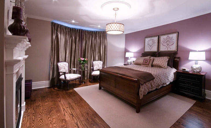 Diseño de dormitorio principal clásico renovado de tamaño medio con paredes púrpuras, suelo de madera oscura, todas las chimeneas y marco de chimenea de madera