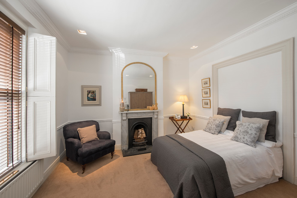 Cette photo montre une chambre avec moquette chic de taille moyenne avec un mur blanc, une cheminée standard, un manteau de cheminée en pierre et un sol beige.