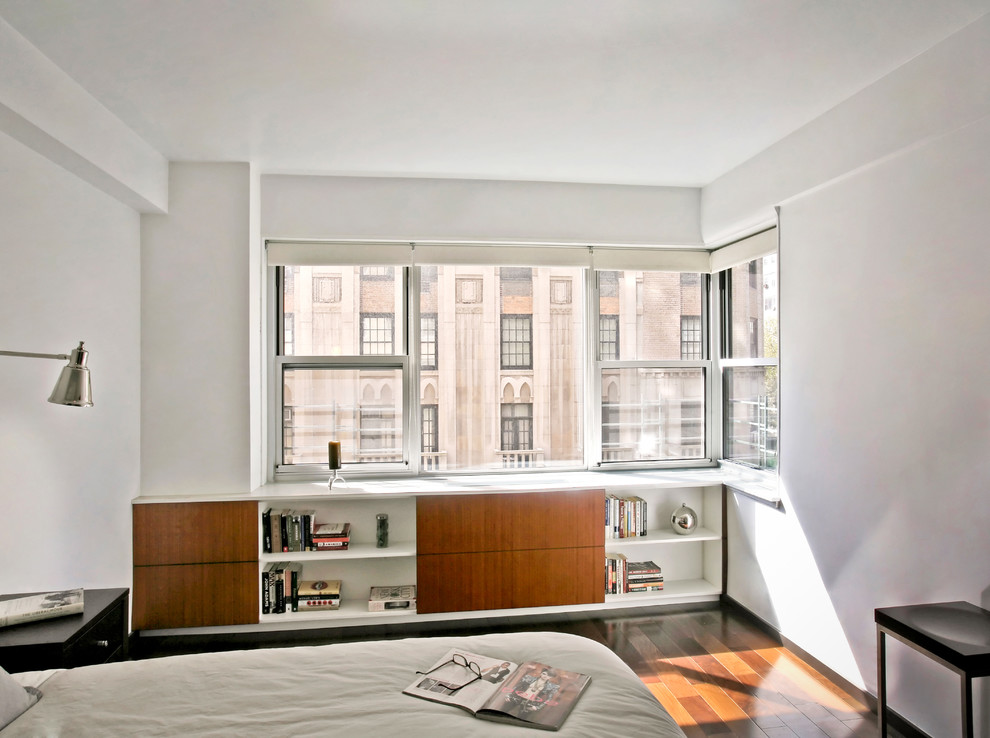 Example of a mid-sized trendy master medium tone wood floor bedroom design in New York with white walls