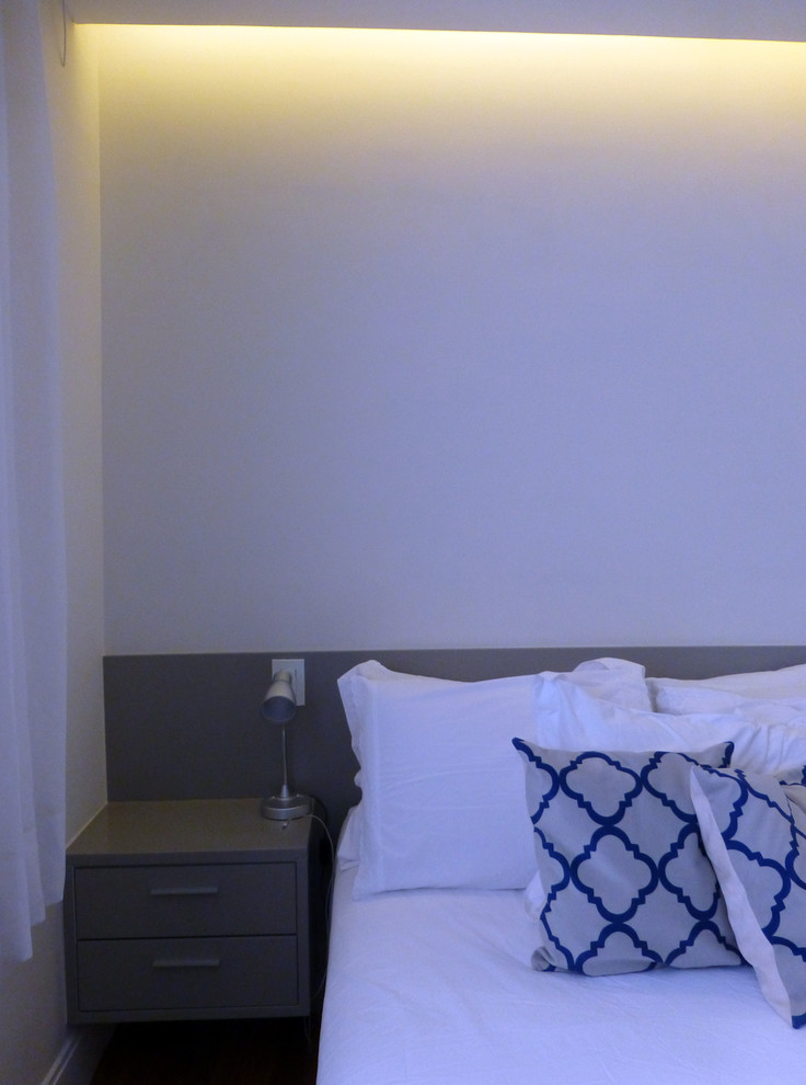 Cette image montre une chambre parentale design de taille moyenne avec un mur beige et parquet foncé.