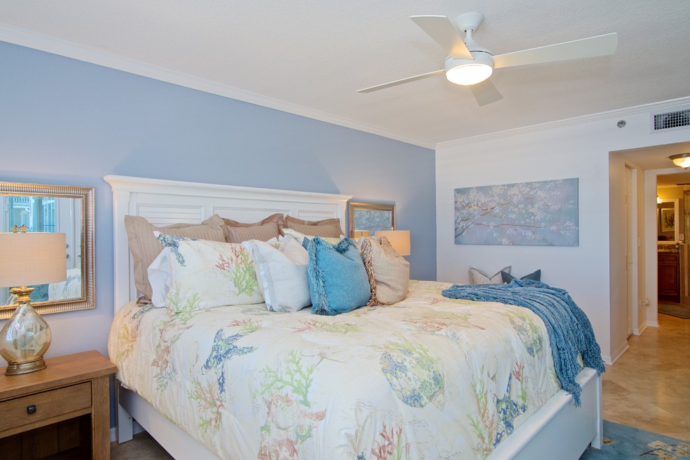 Diseño de dormitorio principal costero de tamaño medio con paredes azules y suelo de travertino