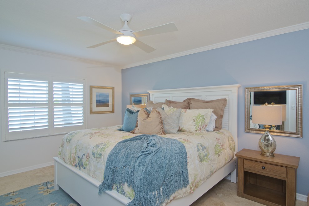 Modelo de dormitorio principal marinero de tamaño medio con paredes azules y suelo de travertino