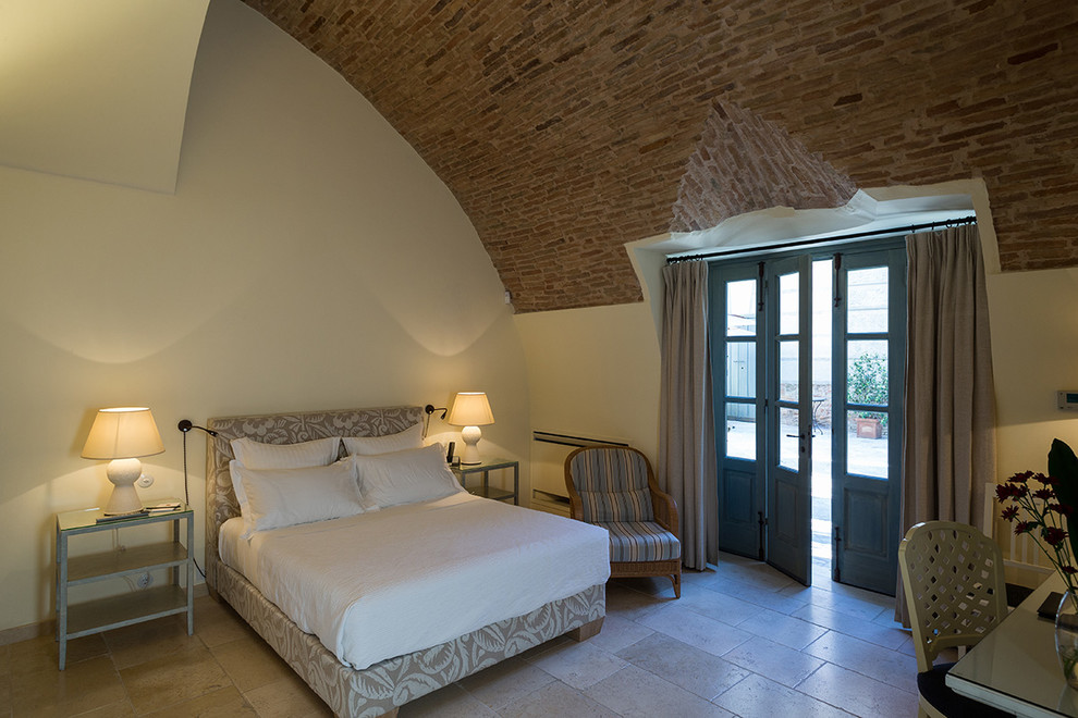 На фото: маленькая гостевая спальня (комната для гостей) с разноцветными стенами, полом из известняка и фасадом камина из камня без камина для на участке и в саду
