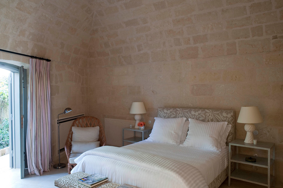 Свежая идея для дизайна: маленькая гостевая спальня (комната для гостей) с бежевыми стенами, полом из известняка, стандартным камином и фасадом камина из камня для на участке и в саду - отличное фото интерьера