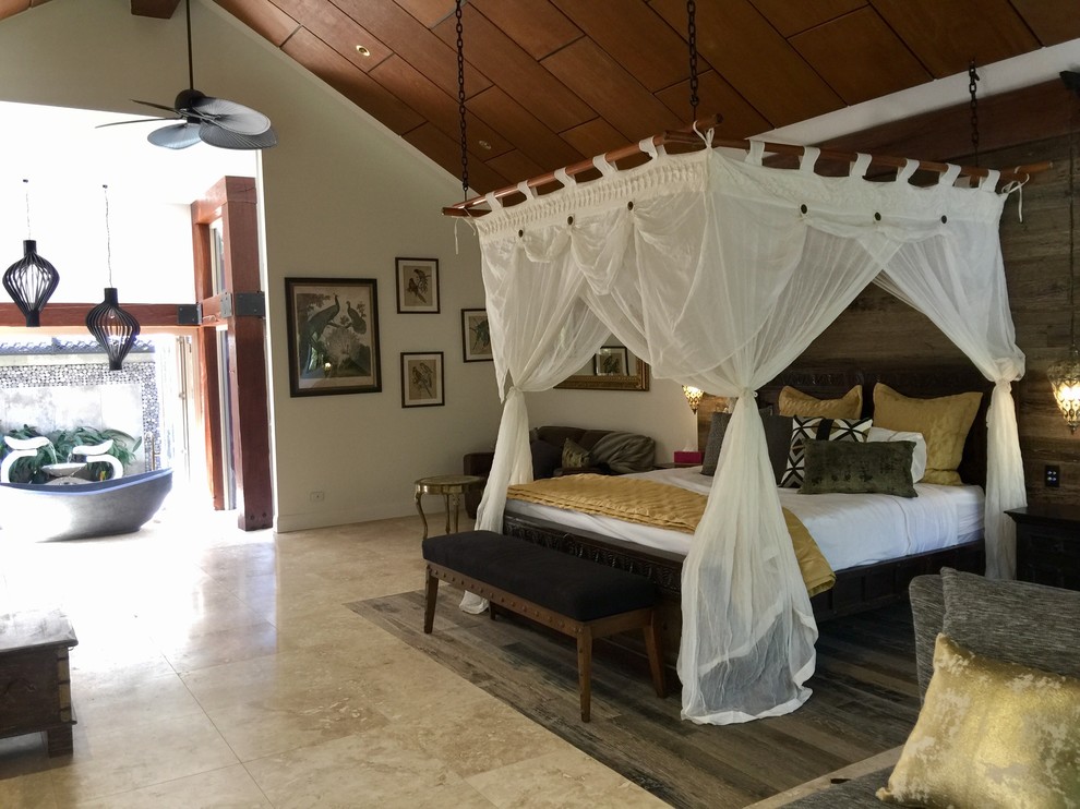 На фото: хозяйская спальня в морском стиле с полом из травертина, двусторонним камином и фасадом камина из камня с