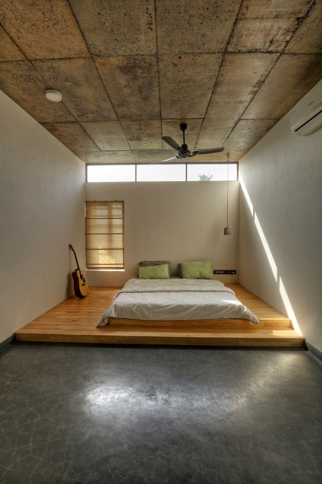 Modelo de dormitorio industrial con paredes blancas, suelo de madera en tonos medios y suelo gris