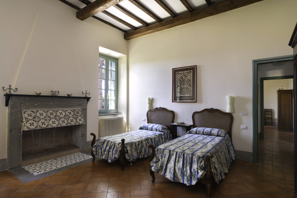 Modelo de habitación de invitados tradicional extra grande con paredes blancas, suelo de ladrillo, todas las chimeneas, marco de chimenea de piedra y suelo marrón