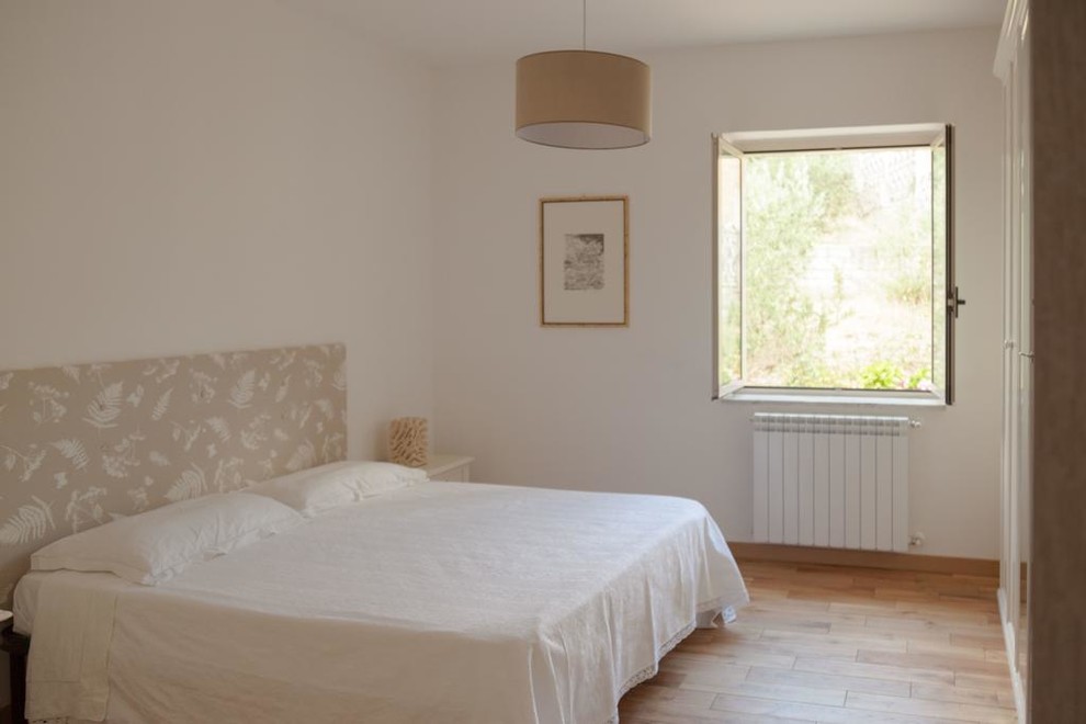 Immagine di una piccola camera matrimoniale contemporanea con pareti bianche, parquet chiaro e pavimento beige