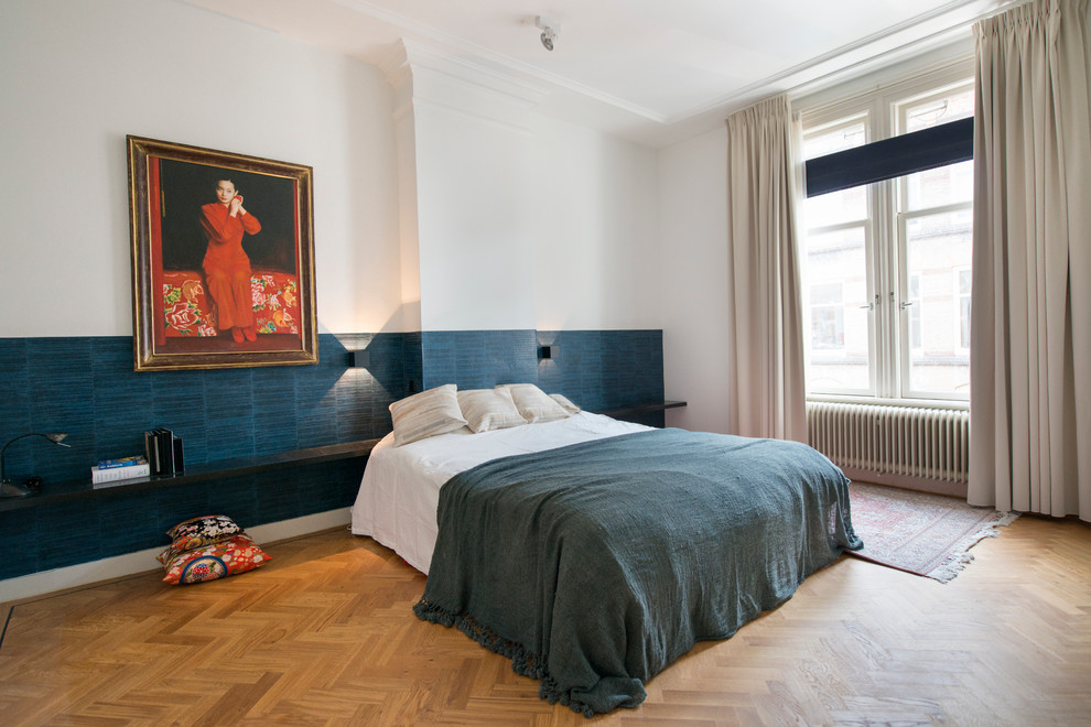 Esempio di una grande camera matrimoniale design con pareti blu e pavimento in legno massello medio