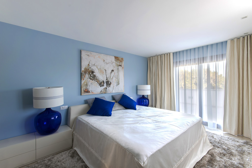 Large modern master bedroom in Palma de Mallorca with blue walls and marble flooring.