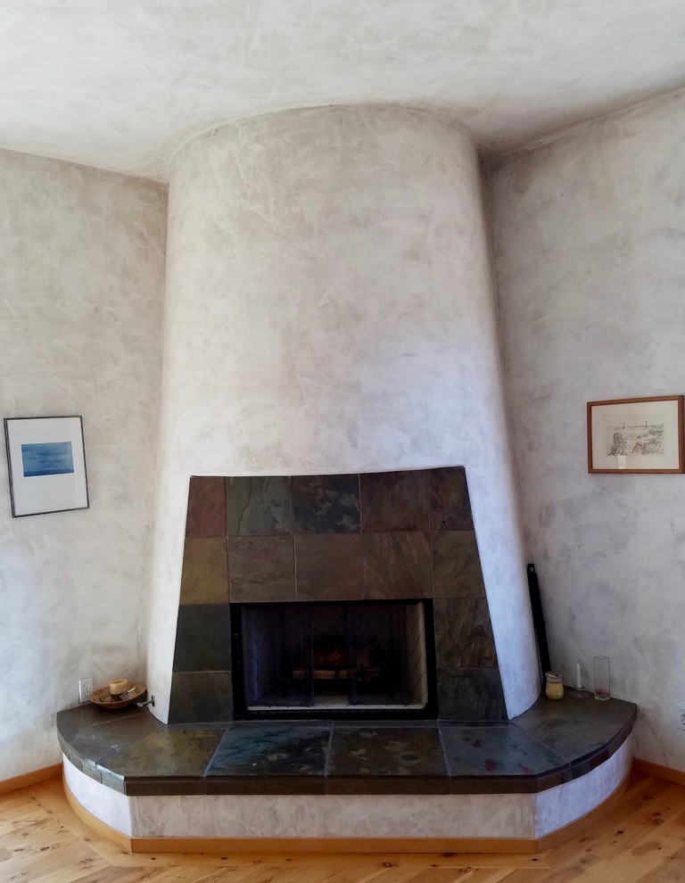 他の地域にある広い地中海スタイルのおしゃれな主寝室 (ベージュの壁、無垢フローリング、標準型暖炉、漆喰の暖炉まわり、茶色い床) のレイアウト