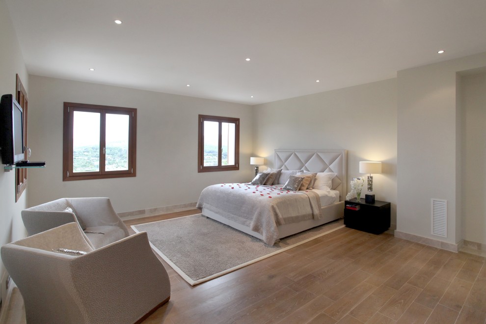 Imagen de dormitorio principal mediterráneo de tamaño medio con paredes blancas y suelo de madera en tonos medios