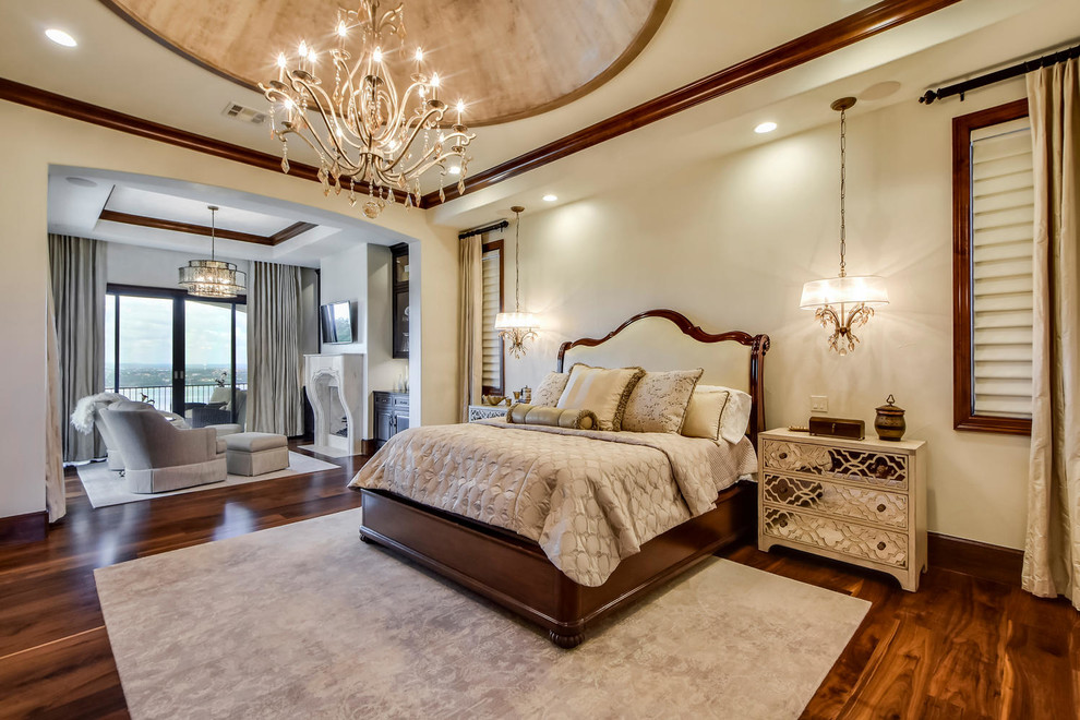 This is an example of a large mediterranean master bedroom in Austin with white walls, medium hardwood flooring, a standard fireplace and a stone fireplace surround.