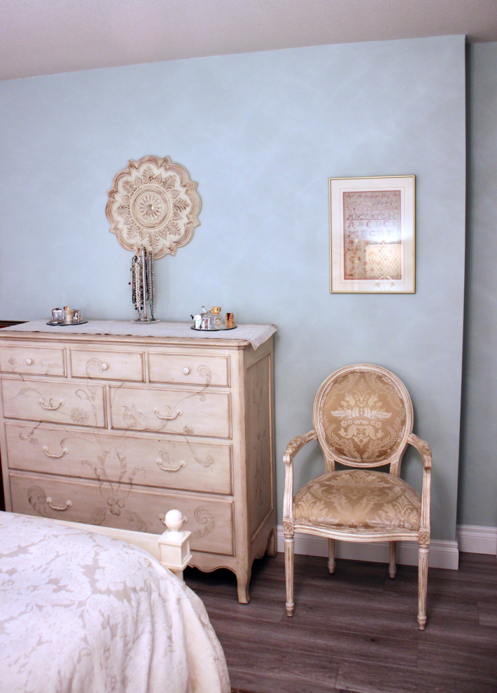 バンクーバーにある中くらいなシャビーシック調のおしゃれな主寝室 (青い壁、ラミネートの床、茶色い床)