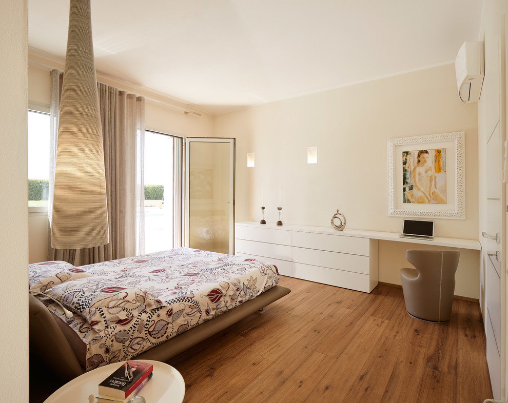 Ispirazione per un'ampia camera matrimoniale design con pareti beige, pavimento in legno massello medio e pavimento marrone