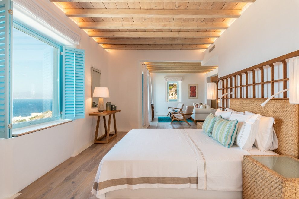 Cette photo montre une chambre bord de mer avec un mur blanc, un sol en bois brun, un sol marron, poutres apparentes et un plafond en bois.