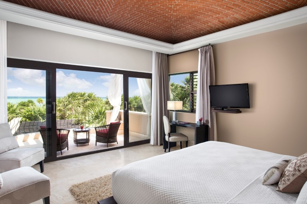 Imagen de dormitorio principal mediterráneo extra grande con paredes beige y suelo de travertino