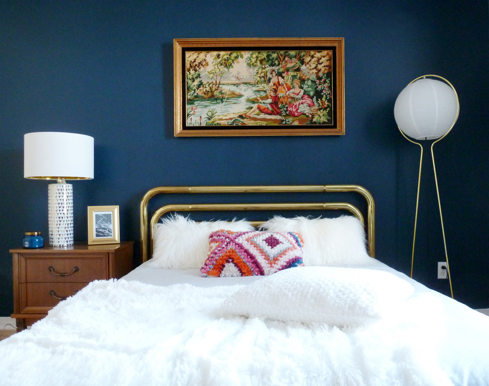 Modelo de dormitorio principal vintage de tamaño medio sin chimenea con paredes azules, suelo de madera clara y suelo marrón