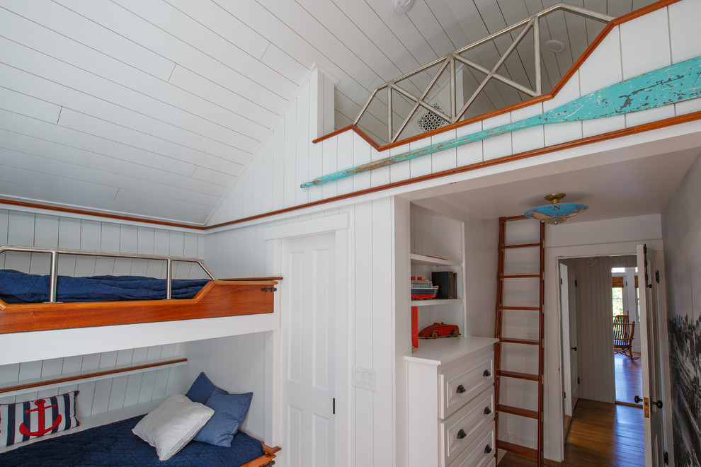 Foto di una camera da letto stile loft costiera di medie dimensioni con pareti bianche, pavimento in legno massello medio e nessun camino