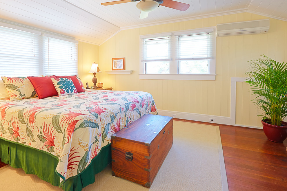 Large world-inspired master bedroom in Hawaii with yellow walls and medium hardwood flooring.