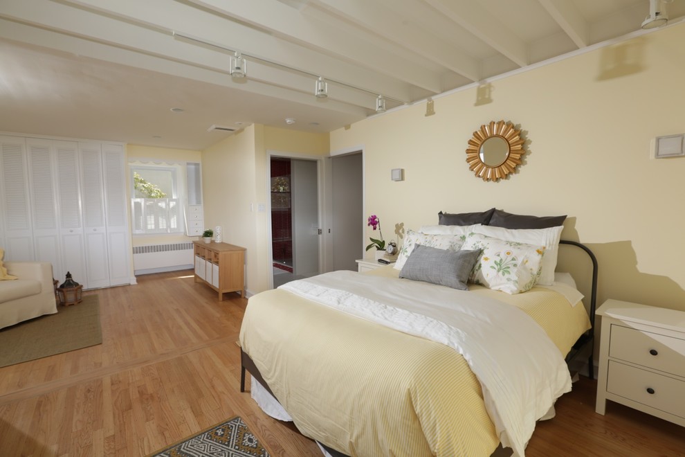Foto de dormitorio principal ecléctico grande sin chimenea con paredes amarillas, suelo de madera clara y suelo marrón