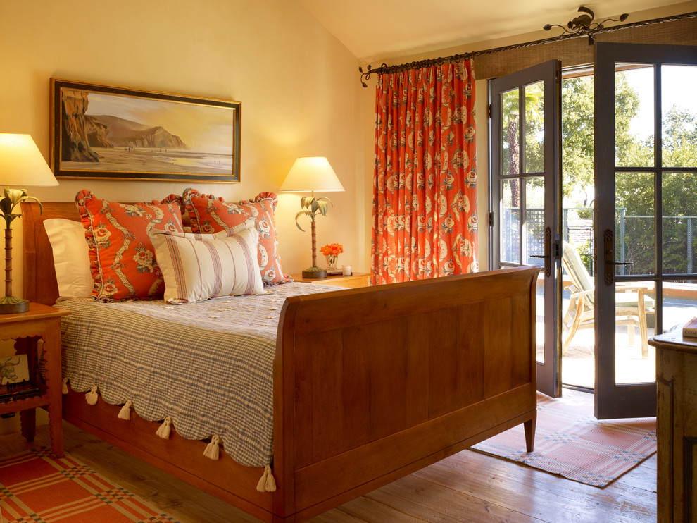 Immagine di un'ampia camera da letto design con pareti gialle, pavimento in legno massello medio e nessun camino