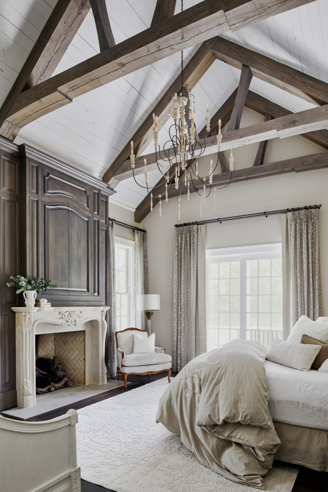 Schlafzimmer mit beiger Wandfarbe, dunklem Holzboden, Kamin, braunem Boden, freigelegten Dachbalken und gewölbter Decke in Sonstige