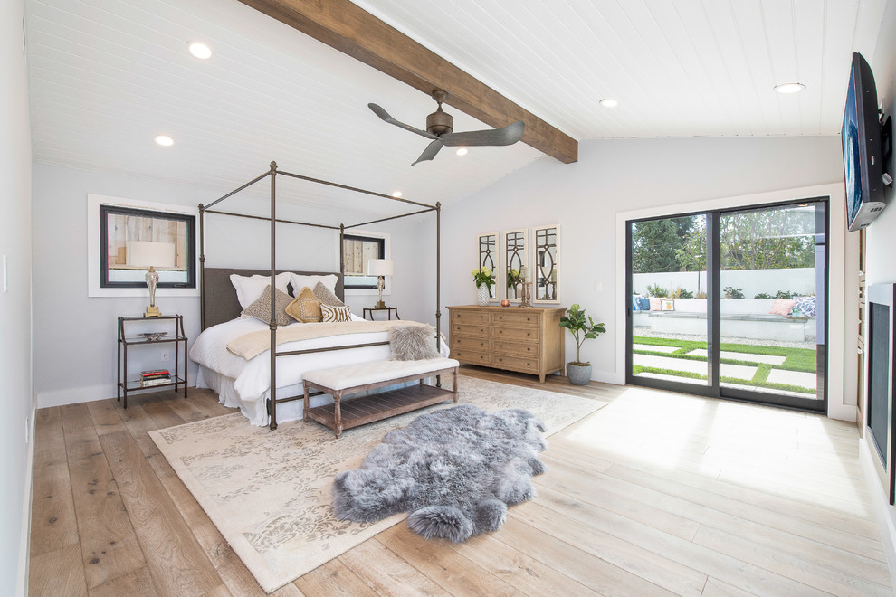 Großes Landhausstil Hauptschlafzimmer mit weißer Wandfarbe, braunem Holzboden, Kamin und braunem Boden in Orange County