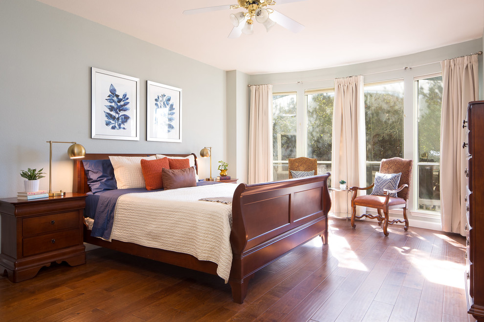 This is an example of a classic master bedroom in Austin with green walls and medium hardwood flooring.