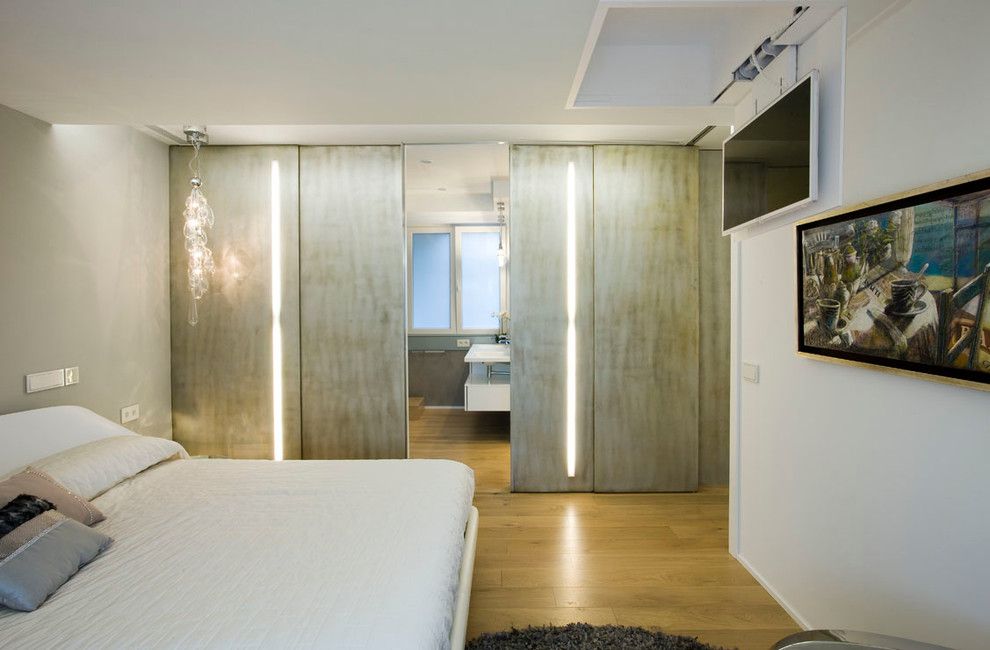 Modelo de dormitorio principal y televisión contemporáneo de tamaño medio sin chimenea con paredes blancas y suelo de madera clara
