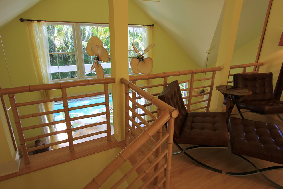 Foto de dormitorio tipo loft exótico de tamaño medio con paredes amarillas y suelo de bambú