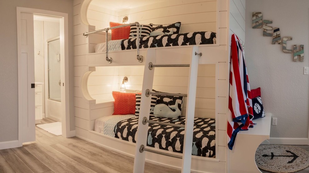 ヒューストンにあるビーチスタイルのおしゃれな客用寝室 (白い壁、ラミネートの床、グレーの床)