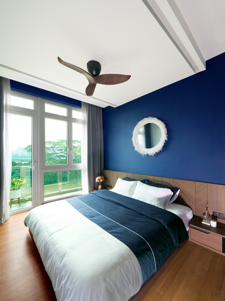 Modernes Schlafzimmer mit blauer Wandfarbe, hellem Holzboden und braunem Boden in Singapur
