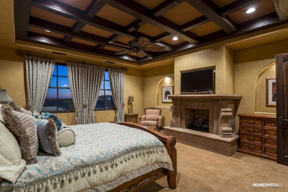 Mediterranes Hauptschlafzimmer mit beiger Wandfarbe, Teppichboden, Gaskamin und Kaminumrandung aus Stein in Phoenix